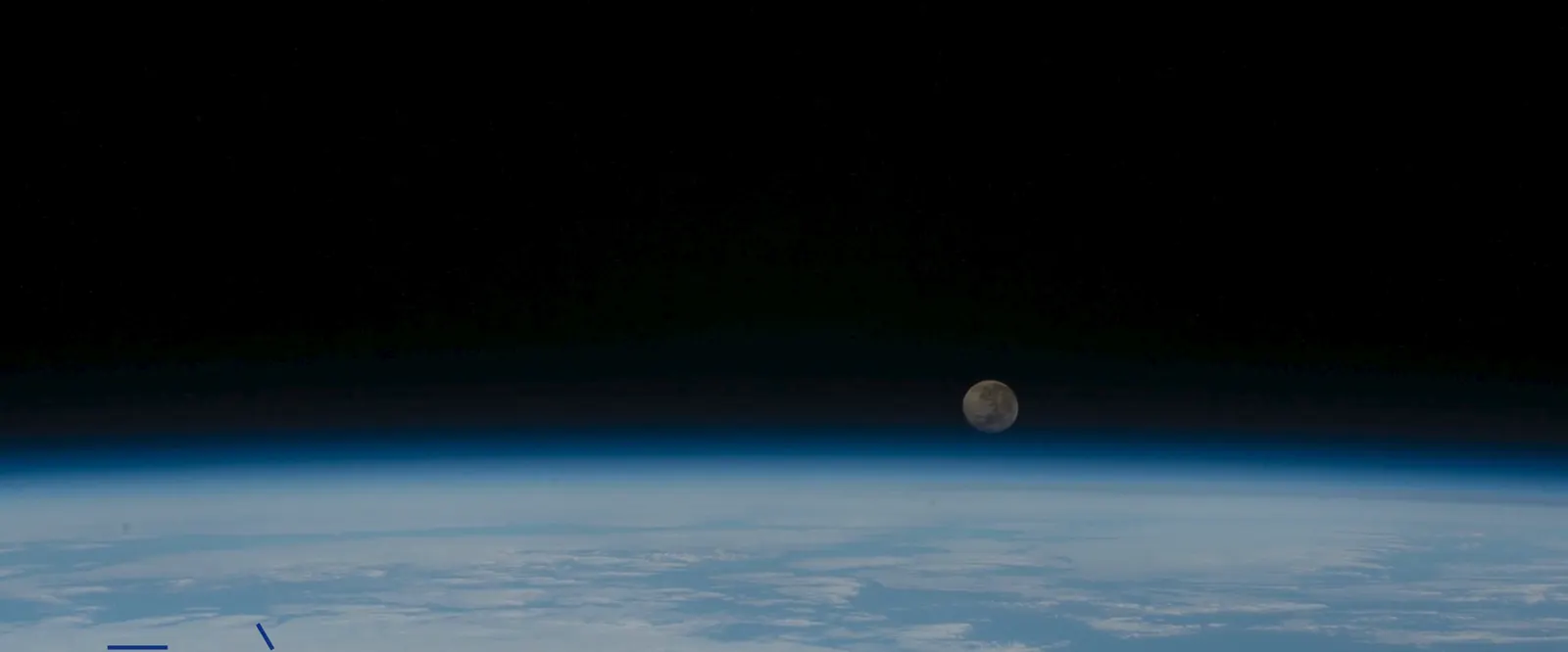 A Lua nascendo sobre o limbo azul da Terra.